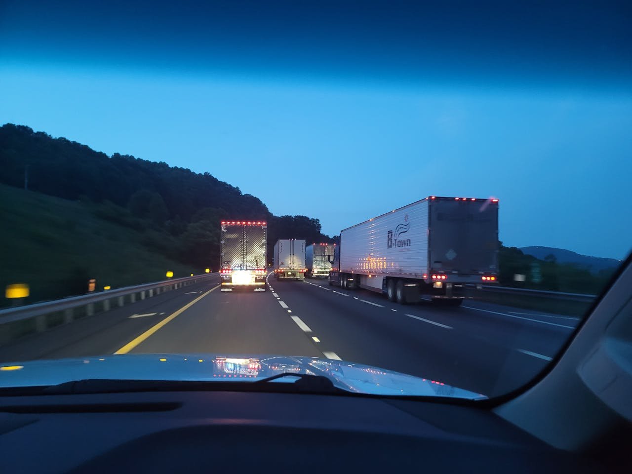 Truck in front of Car on Road in Evening